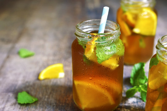Orange iced tea in a glass jar with paper straws.