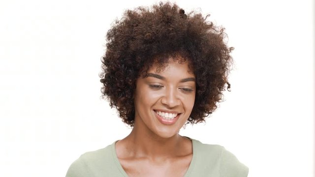 Shy young beautiful african girl laughing over white background.