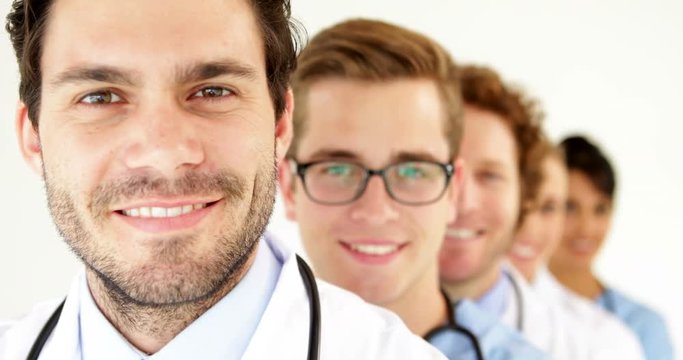 Team of doctors standing in row smiling at camera