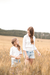 Fototapeta premium Two girl standing in rye field outdoors. Looking at each other. Childhood. Summer time.