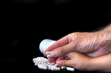 Adult and child hands holding medical pills. Treatment concept.