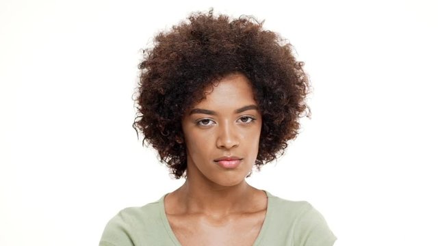 Displeased young beautiful african girl over white background. Slow motion.