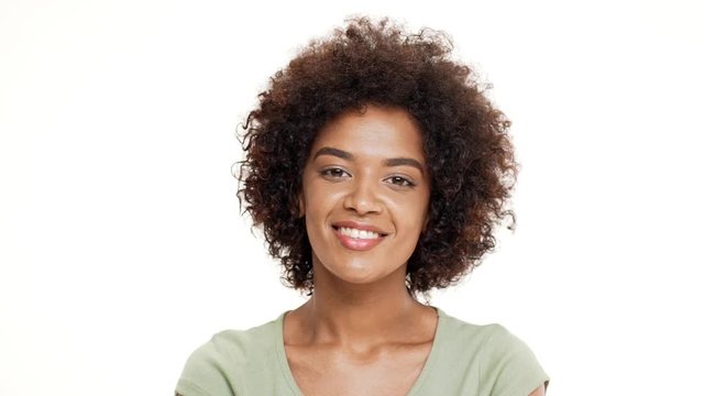 Young beautiful african girl smiling over white background. Slow motion.