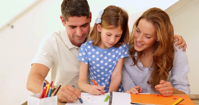 Cute parents and daughter colouring together