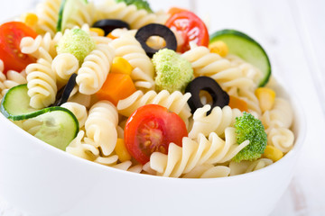 Pasta salad in a bowl on white wood table



