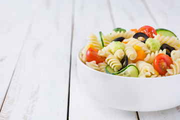 Pasta salad in a bowl on white wood table



