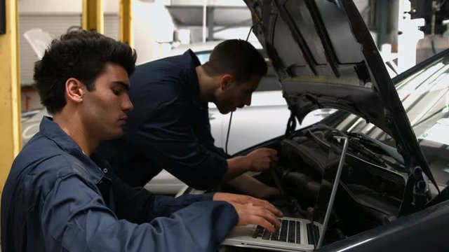 Handsome mechanics overhauling a car in the garage