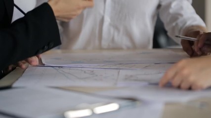 Active discussion of charts and plans on paper with your hands and pencils behind a desk. - Powered by Adobe