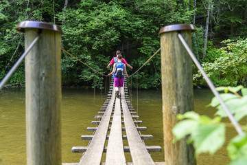 Zwei Wanderer überqueren einen Fluß über eine Hängebrücke