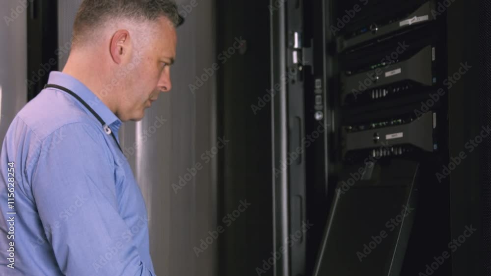 Poster technician using laptop to analyse server