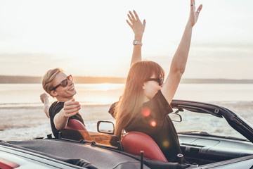 Fototapeta premium young happy couple in cabriolet in sunset light