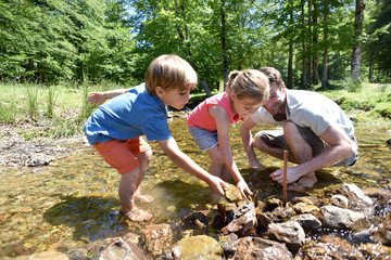 Father and kids in river building a dam with pebbles © goodluz