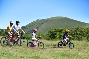 Parents with kids riding bikes in moutain path © goodluz
