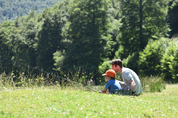 Naklejka na ściany i meble Dad with little boy fishing by mountain lake