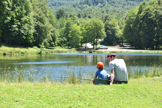 Father and son fishing together by mountain lake