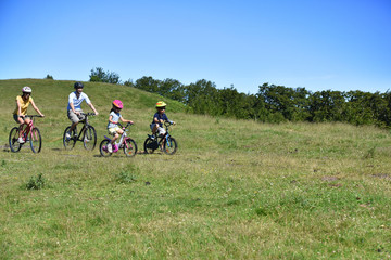 Obraz premium Parents with kids riding bikes in moutain path