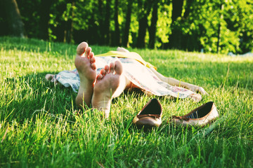 girl lying in grass barefoot without shoes in summer sun - 115630470