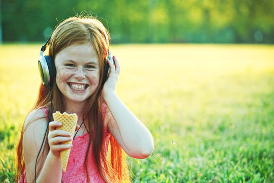 girl with freckles eating ice cream and listening to music