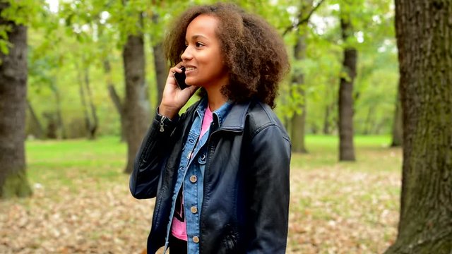 young african chatty smile girl talks with friend through the smartphone in the forest