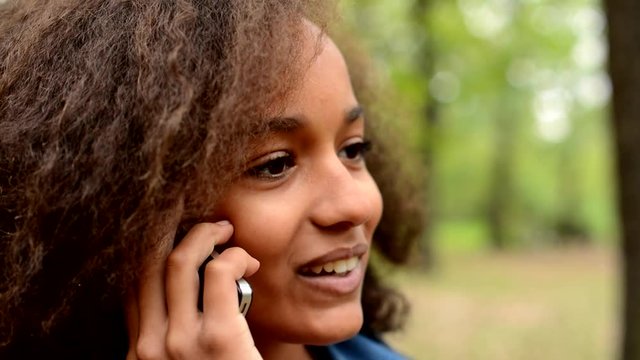 young chatty happy african girl talk with friend through the smartphone in the forest - staisfied - face detail