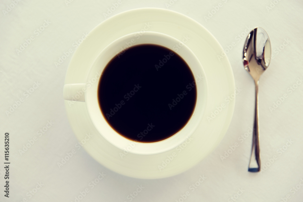 Wall mural cup of black coffee with spoon and saucer on table