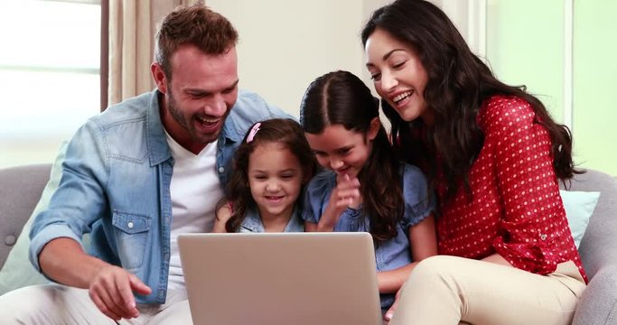 Happy family using laptop on sofa 
