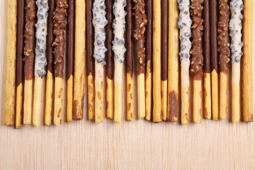 Assorted chocolate dipped biscuit sticks on wooden surface