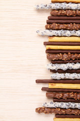 Assorted chocolate dipped biscuit sticks on wooden surface