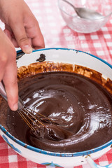 Hand mixing melted chocolate cream with flour