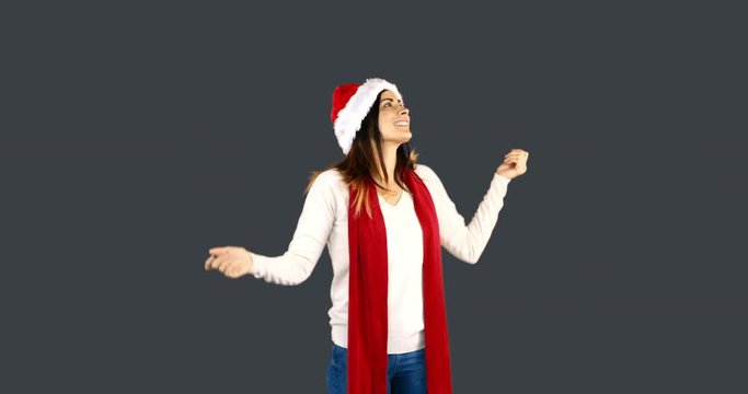 Woman in santa hat and warm clothing looking upwards on grey background