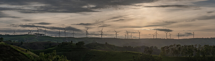 Fototapeta na wymiar Wind turbine generator silhouette panorama with twilight sky background. 