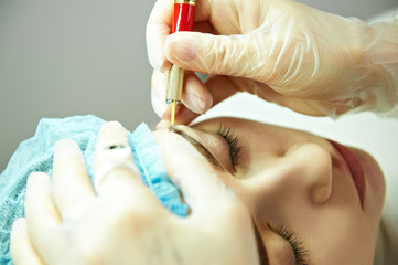 Cosmetician making permanent eyebrow make up