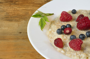 Oatmeal in plate on wooden background