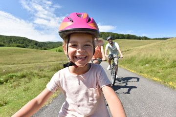 Obraz premium Portrait of little girl riding bike with family