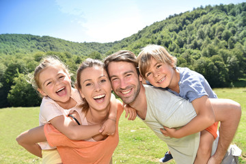 Parents giving piggyback ride to kids in mountains