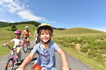 Portrait of little boy riding bike with family