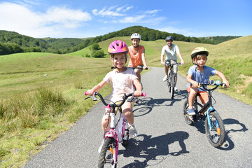 Naklejka premium Happy family riding bikes in mountain road