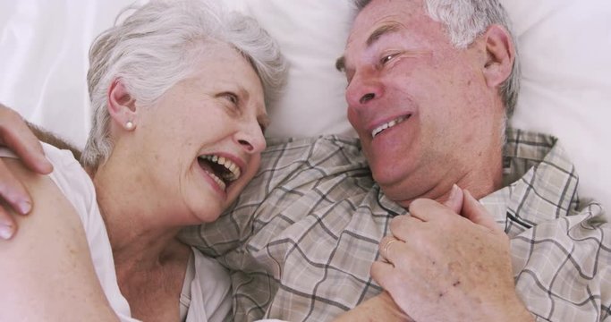 Senior couple smiling in bed