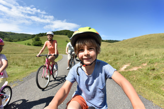 Portrait of little boy riding bike with family
