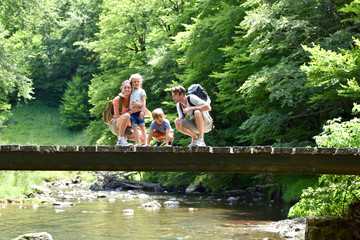 Family of four walking on a bridge crossing the river