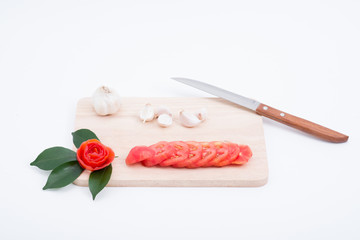 Garlic and tomatoes on a cutting board.