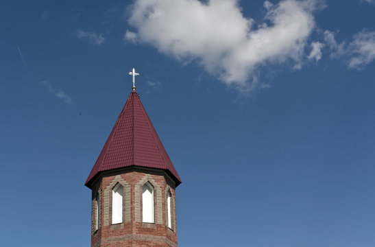 Catholic church tower against blue sky.