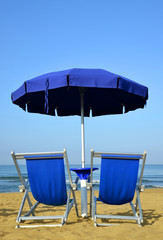 Sun loungers and umbrella on a sandy beach. Vacation concept.