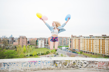 Young beautiful blonde caucasian girl playing with colorful balo
