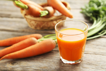 Fresh carrot juice in glass on a grey wooden table