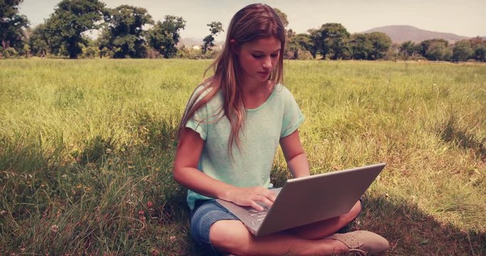 Pretty blonde relaxing in the park with her laptop on a sunny day 