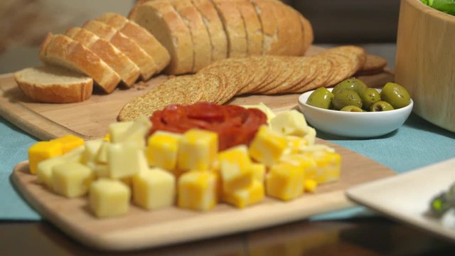 Cubed Cheese Rack Focus Crackers. camera racks focus from sliced bread and cracker spread to cubed cheese variety and pepperoni, then back again. Olives in scene too
