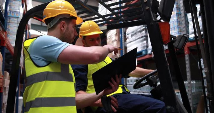 Warehouse worker talking with forklift driver in 4k video format