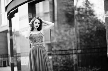 Fototapeta na wymiar Portrait of fashionable girl at red evening dress posed background mirror window of modern building. Black and white photo