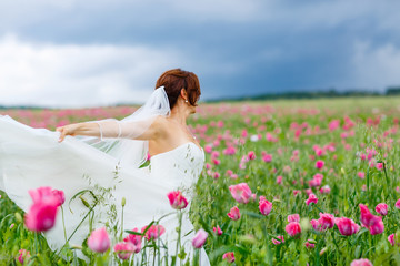 Naklejka na ściany i meble happy bride in white dress having fun in flower poppy field 